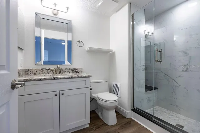 a bathroom with a granite countertop sink toilet and shower
