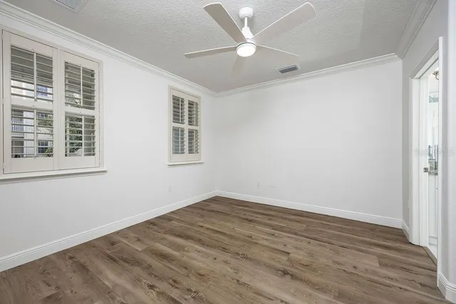 a view of empty room with wooden floor and fan