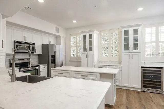 a large kitchen with stainless steel appliances kitchen island granite countertop a refrigerator and a stove top oven