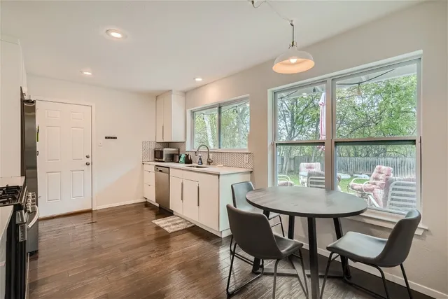 a kitchen that has a dining table chairs and white cabinets