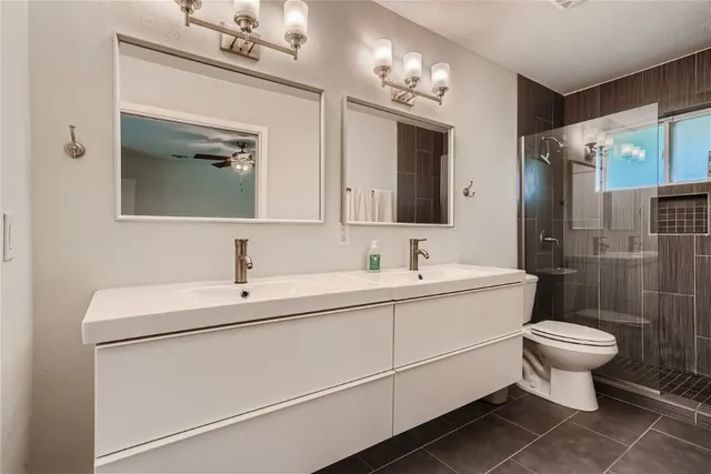 a bathroom with a toilet sink double vanity and mirror