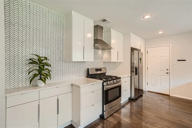 a kitchen that has a dining table chairs and white cabinets