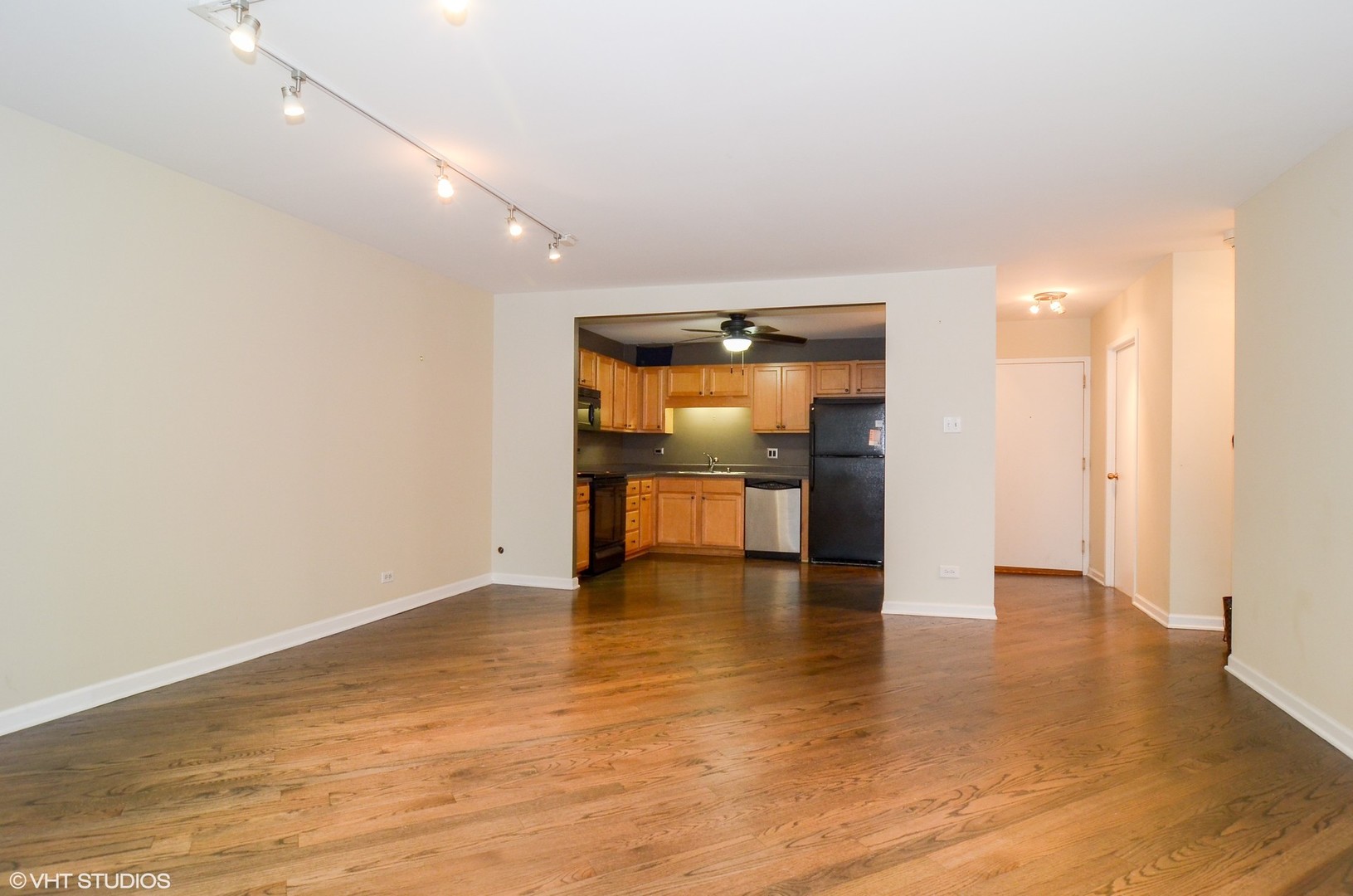 211 East Ohio Street, Unit 809 Chicago, IL 60611 - Photo 5 of 17 an empty room with wooden floor and a kitchen space