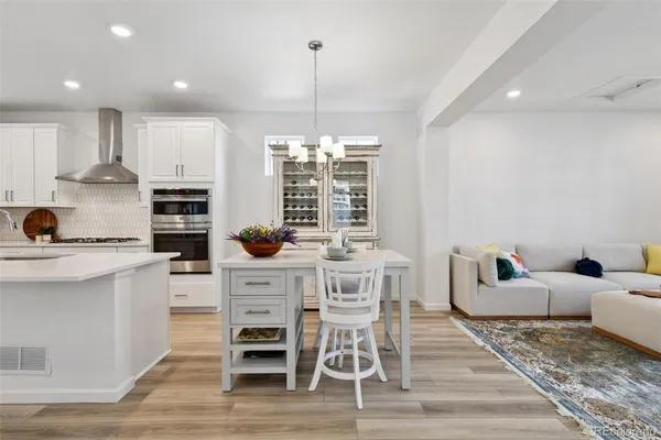 a kitchen with stainless steel appliances granite countertop a stove top oven a sink dishwasher and white cabinets with wooden floor