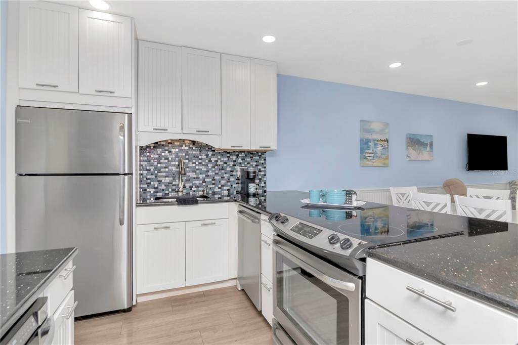 4390 Exeter Drive, Unit 305 Longboat Key, FL 34228 - Photo 15 of 78 a kitchen with granite countertop a sink stainless steel appliances and white cabinets