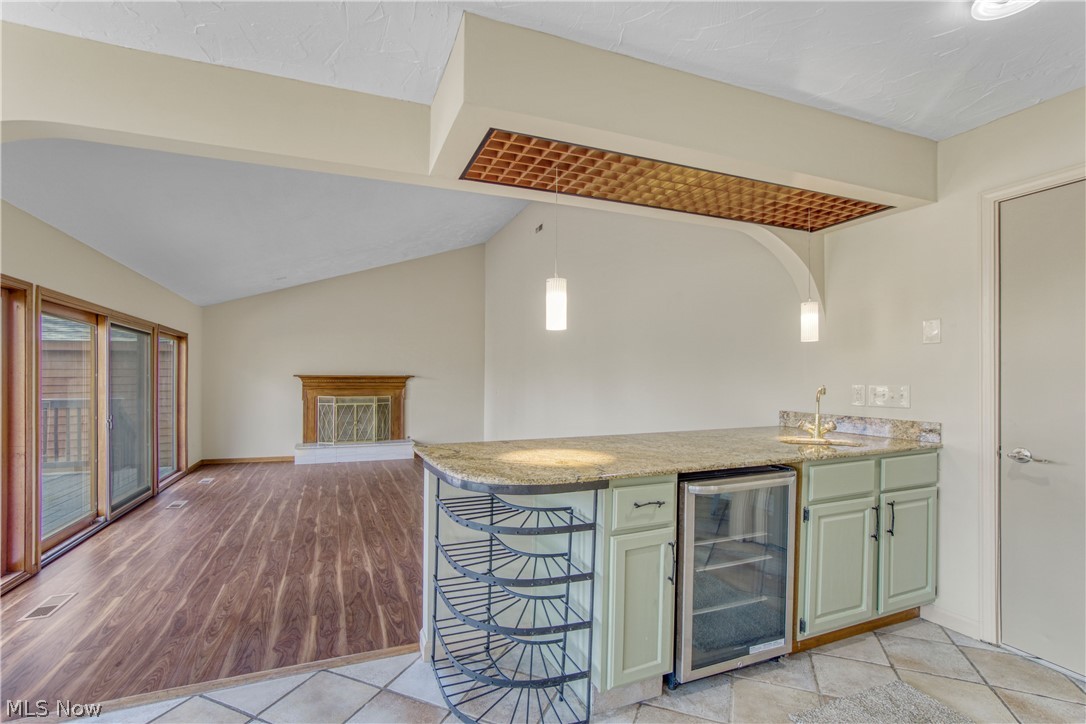 29329 Eddy Road Wickliffe, OH 44092 - Photo 13 of 50 Kitchen with light stone counters, lofted ceiling, light tile floors, decorative light fixtures, wine rack, wet bar and beverage cooler