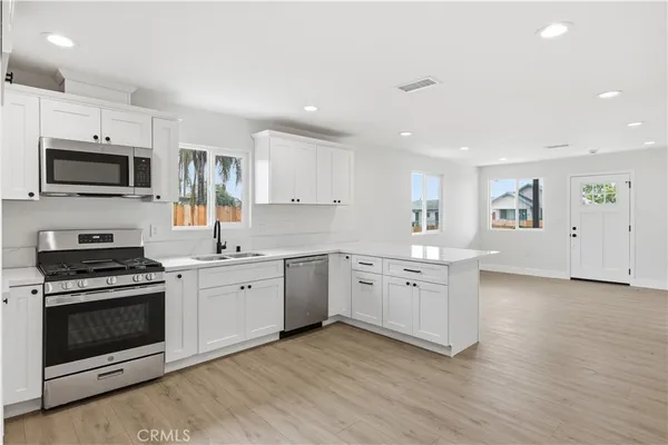 a large kitchen with cabinets wooden floor and stainless steel appliances