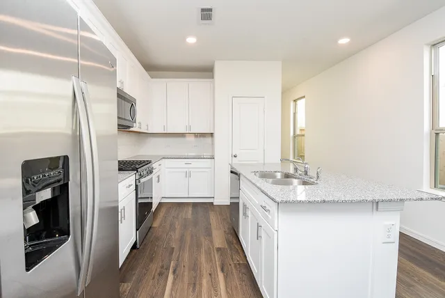 a kitchen with granite countertop a sink a stove and cabinets