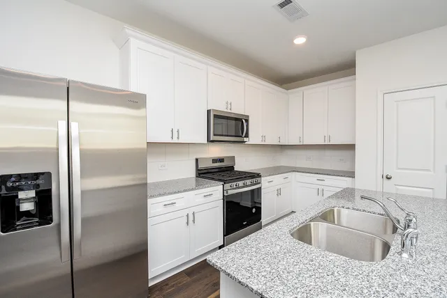 a kitchen with stainless steel appliances granite countertop a stove a sink and a microwave