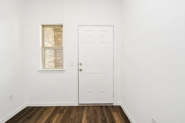 a view of a small space with wooden floor and a window