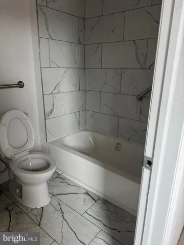 a bathroom with a granite countertop toilet and a sink