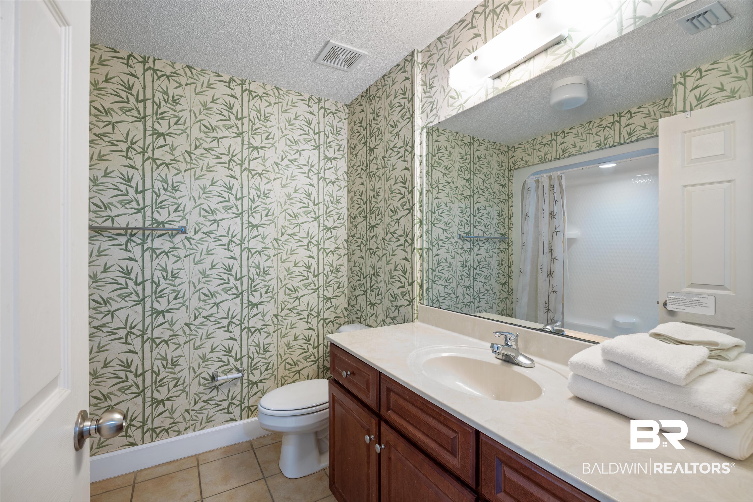 27580 Canal Road, Unit 1431 Orange Beach, AL 36561 - Photo 27 of 73 Full bathroom featuring a shower with curtain, light tile patterned floors, a textured ceiling, vanity, and wallpapered walls