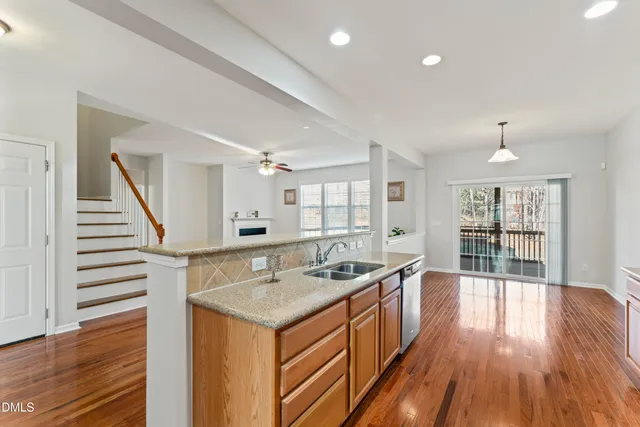 a view of a kitchen with stainless steel appliances granite countertop a stove top oven a refrigerator a sink and dishwasher with wooden floor