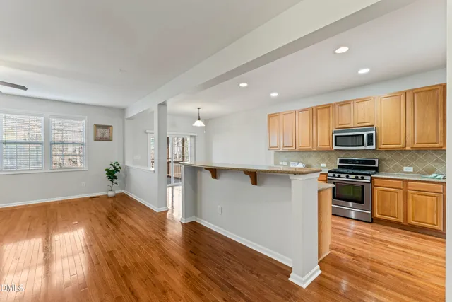 a kitchen with stainless steel appliances a stove top oven a sink dishwasher and a refrigerator with wooden floor