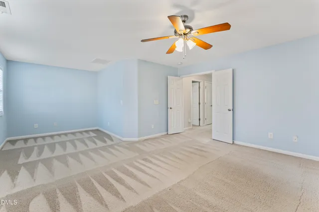 a view of an empty room with chandelier fan