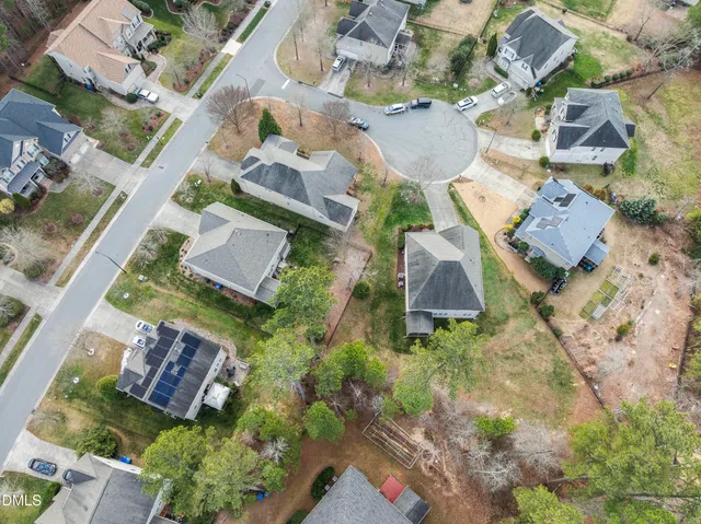 an aerial view of a house with swimming pool and large trees