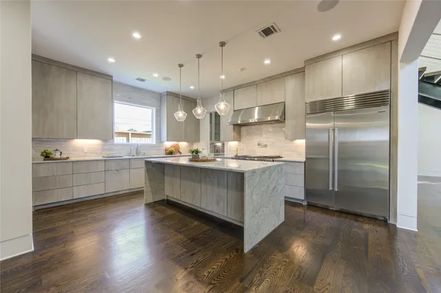 a dining hall with stainless steel appliances kitchen island granite countertop a refrigerator and a wooden floor