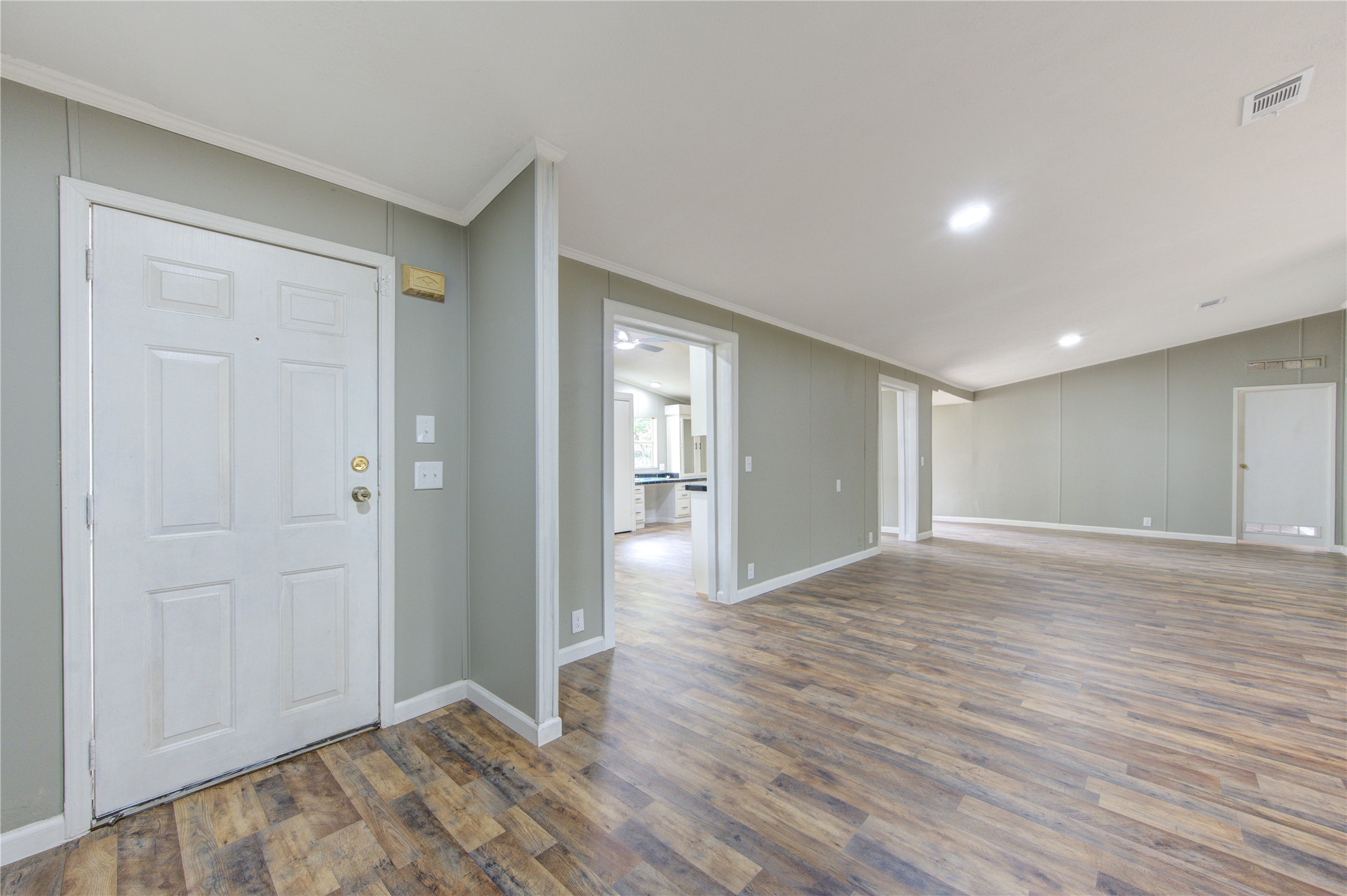 30226 Davis Street Magnolia, TX 77355 - Photo 5 of 50 This spacious, open-concept area features laminate wood flooring and neutral wall colors, providing a bright and inviting atmosphere. With ample natural light and access to adjacent rooms, it's perfect for versatile living arrangements.