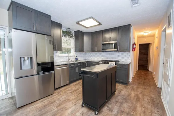 a kitchen with stainless steel appliances granite countertop a refrigerator a stove a sink and a microwave