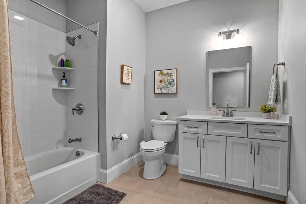 8 Sanborn Street, Unit 2012 Reading, MA 01867 - Photo 22 of 36 a bathroom with a granite countertop sink a toilet a mirror a vanity and bathtub