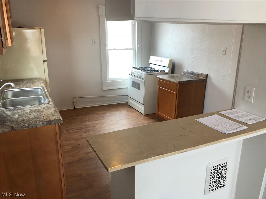 4016 Riverside Avenue Cleveland, OH 44109 - Photo 16 of 25 Kitchen featuring white appliances, dark hardwood / wood-style flooring, sink, and kitchen peninsula