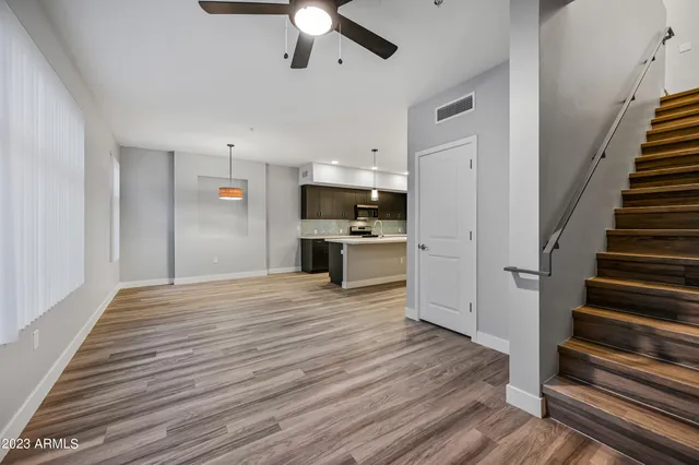 a view of a kitchen with wooden floor electronic appliances and a ceiling fan