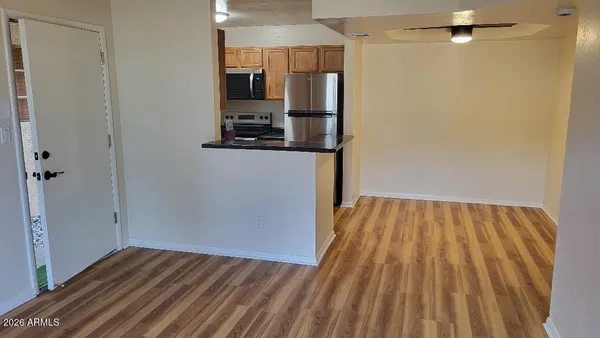 a view of empty room with wooden floor and fan