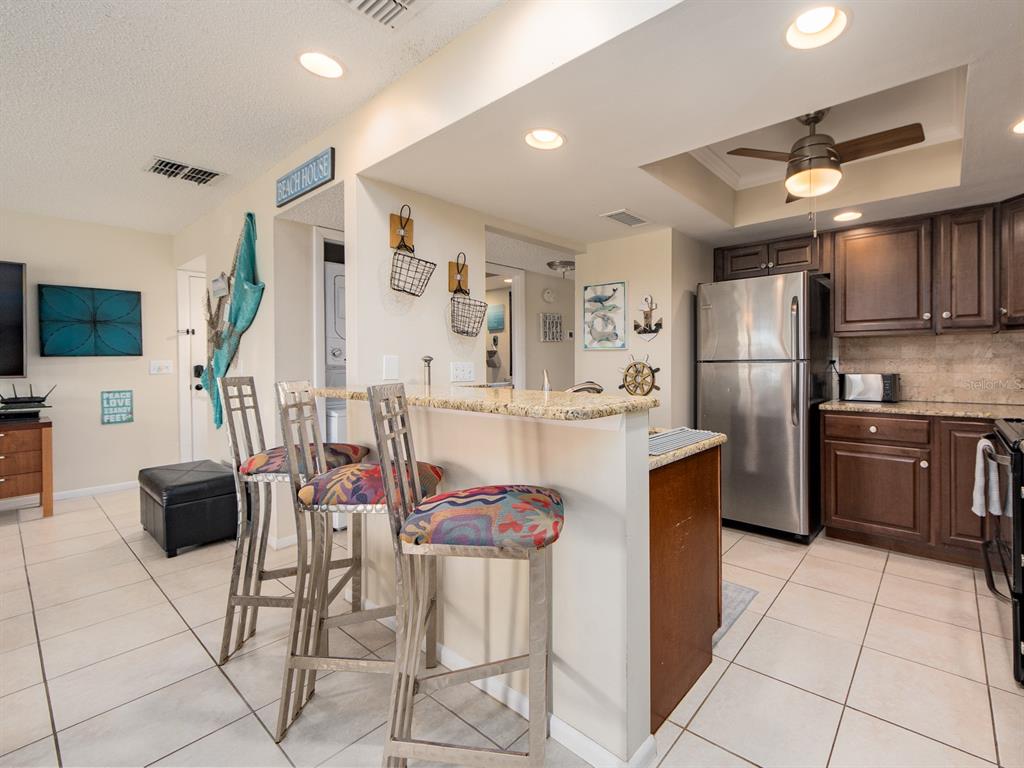 2406 Gulf Boulevard, Unit 204 Indian Rocks Beach, FL 33785 - Photo 13 of 39 a kitchen with stainless steel appliances kitchen island granite countertop a refrigerator and a stove top oven