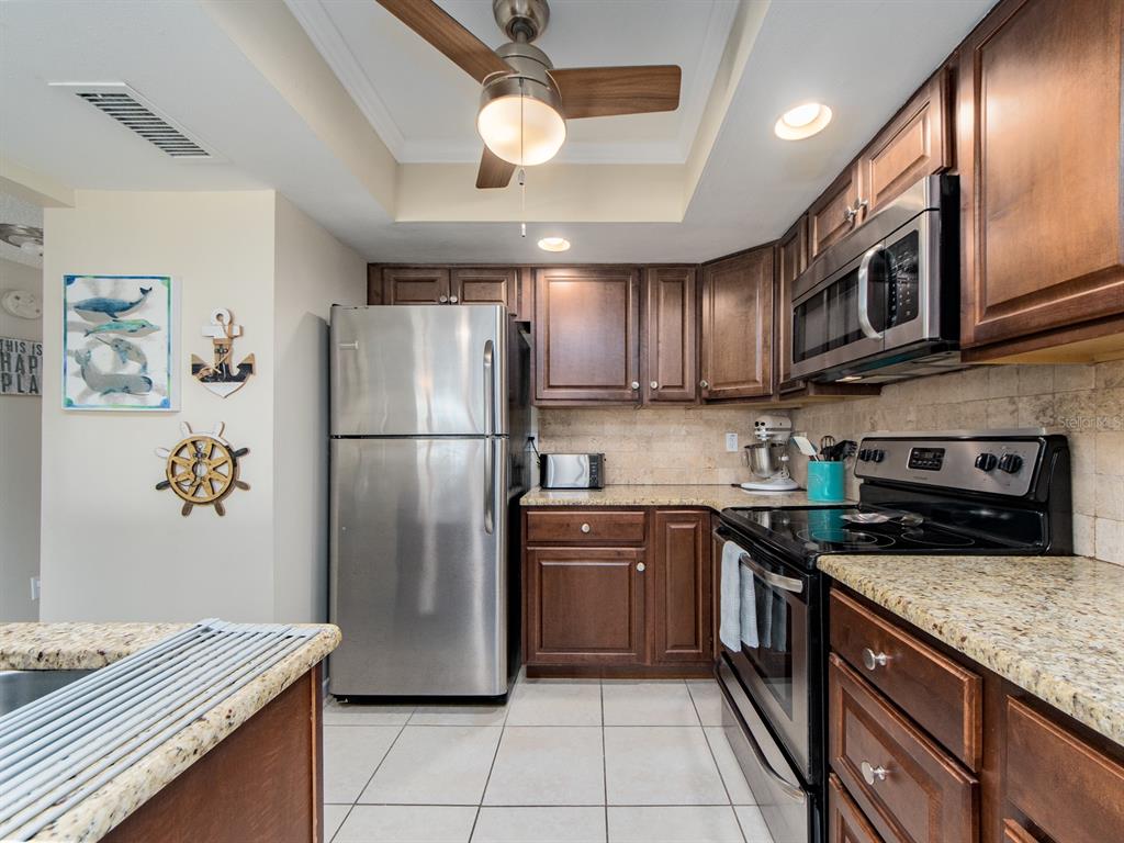 2406 Gulf Boulevard, Unit 204 Indian Rocks Beach, FL 33785 - Photo 14 of 39 a kitchen with stainless steel appliances granite countertop a refrigerator a stove a sink and a microwave