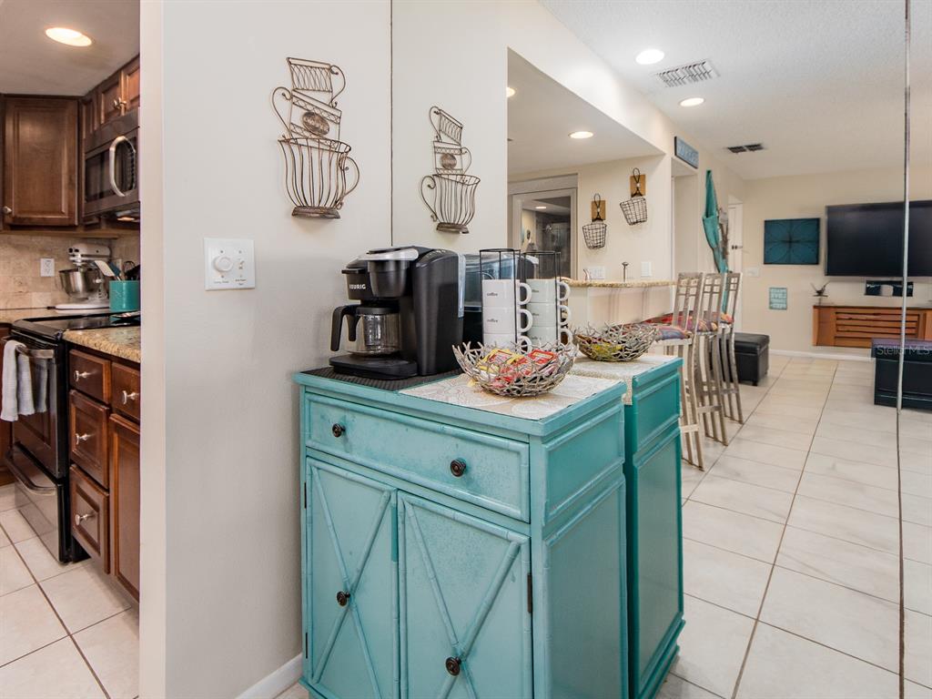 2406 Gulf Boulevard, Unit 204 Indian Rocks Beach, FL 33785 - Photo 16 of 39 a kitchen with stainless steel appliances kitchen island granite countertop a stove a sink and a refrigerator with wooden floor