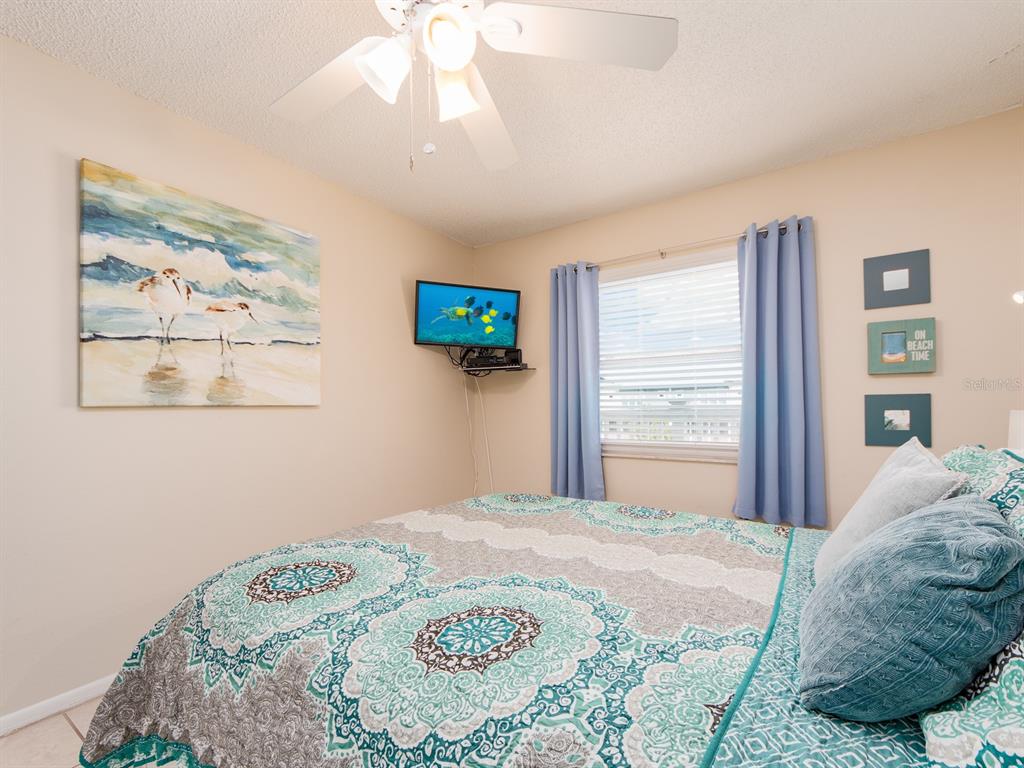 2406 Gulf Boulevard, Unit 204 Indian Rocks Beach, FL 33785 - Photo 28 of 39 a bedroom with a bed and a painting on the wall