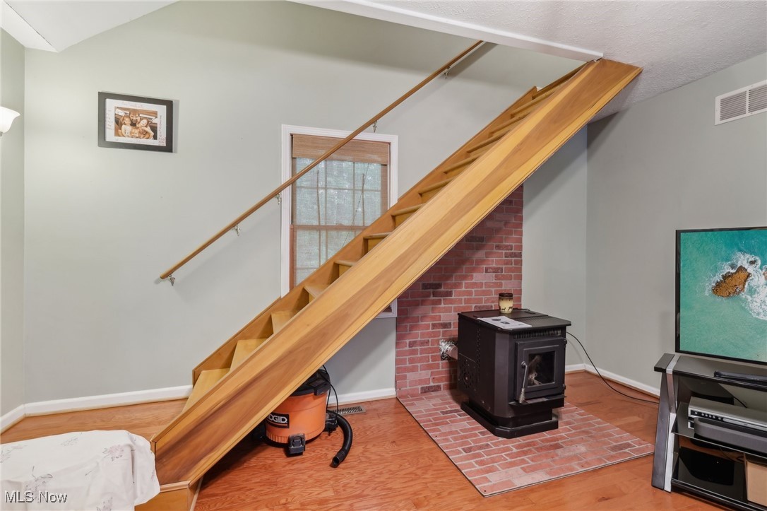 2490 Dodgeville Road Rome, OH 44085 - Photo 10 of 42 Stairway with wood finished floors, baseboards, a wood stove, and lofted ceiling