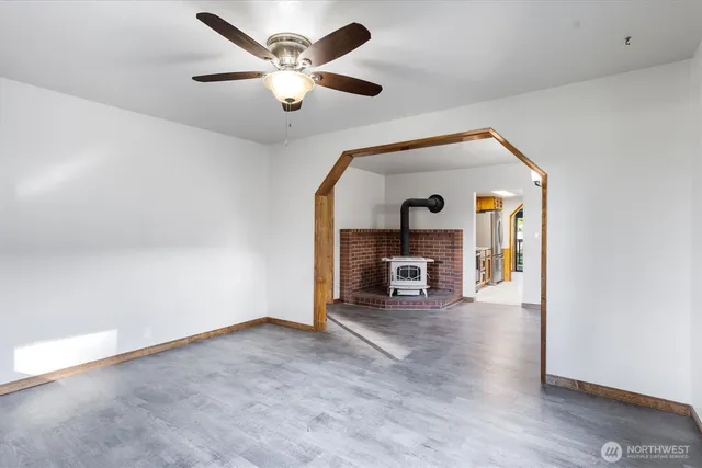 a view of an empty room with a fireplace and a ceiling fan