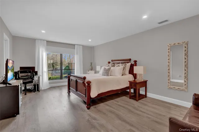 a spacious bedroom with a bed and wooden floor