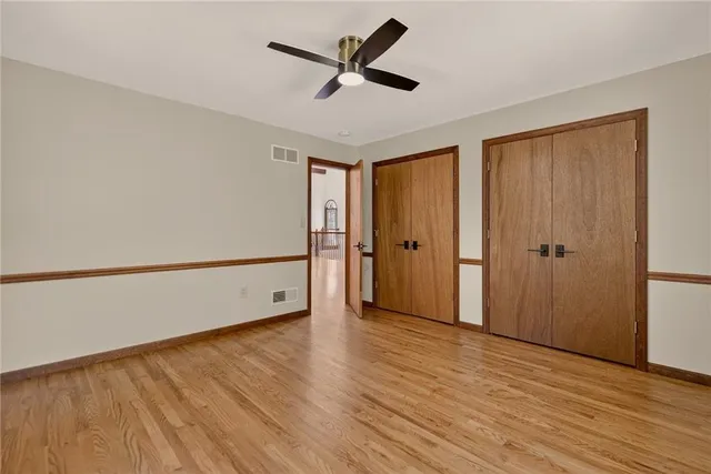 an empty room with wooden floor and a ceiling fan