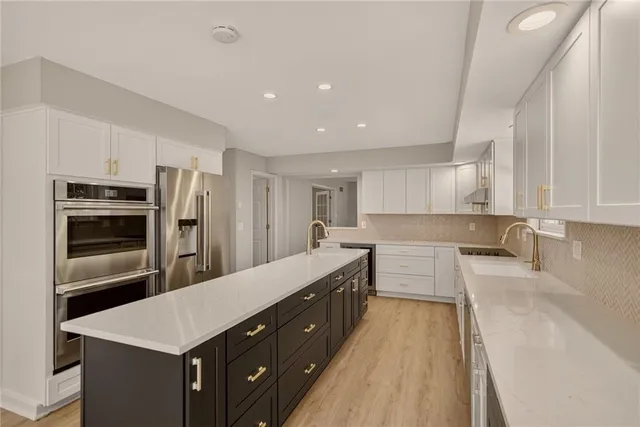 a large kitchen with a large counter top stainless steel appliances and cabinets