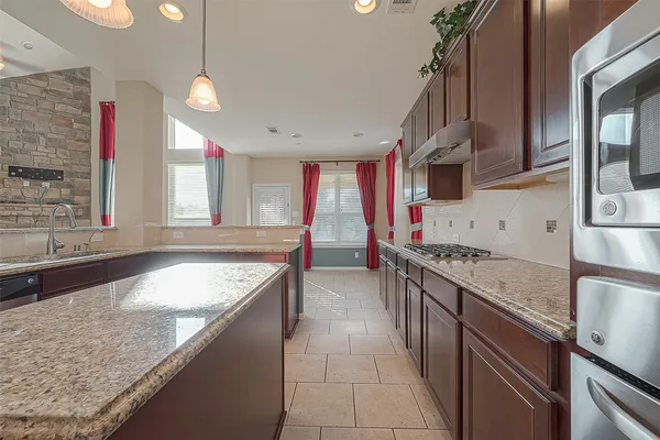 a kitchen with stainless steel appliances granite countertop a sink a stove and a wooden floors