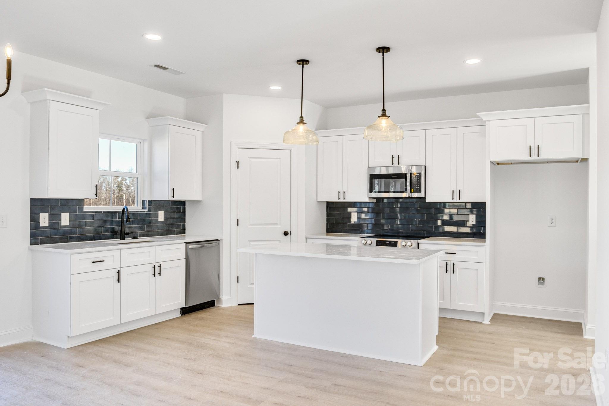 a kitchen that has a lot of white cabinets and stainless steel appliances