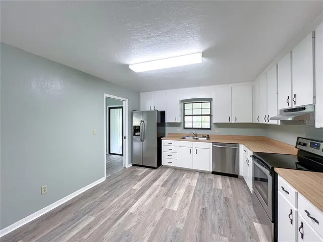 a kitchen with granite countertop a stove cabinets and wooden floor
