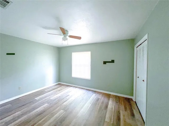 a view of empty room with wooden floor and fan