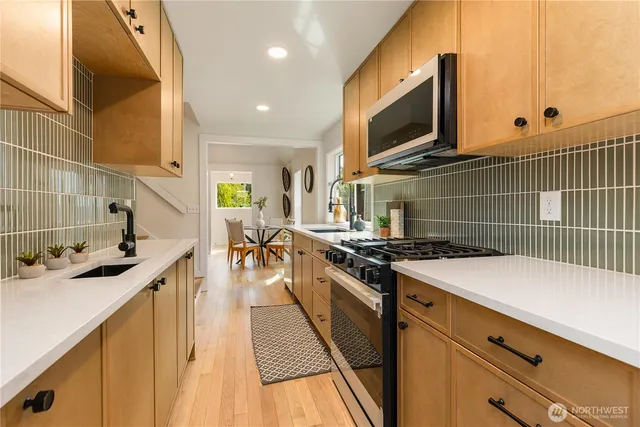 a kitchen with stainless steel appliances a stove a sink a oven and wooden cabinets