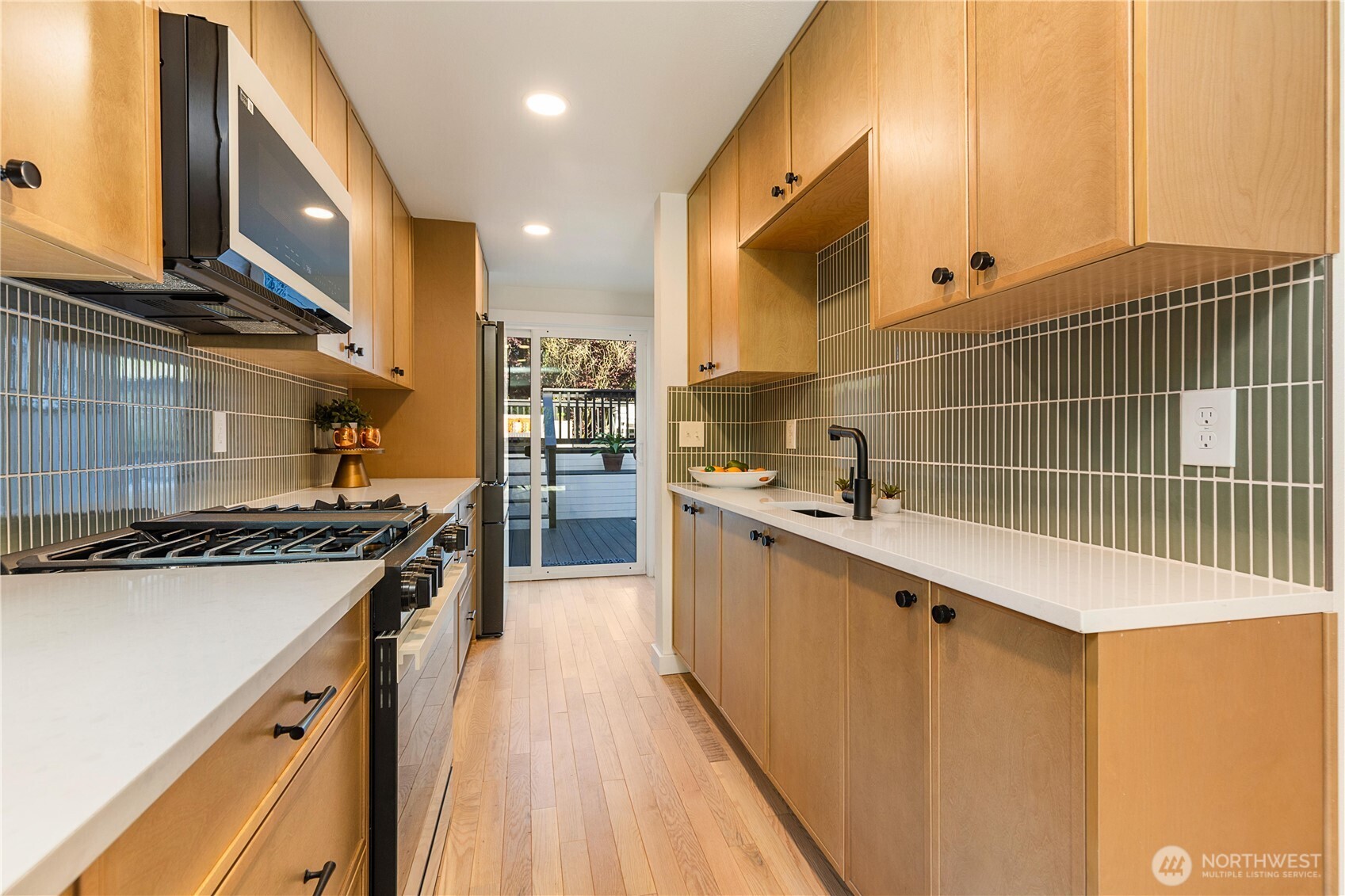 6031 McKinley Place North Seattle, WA 98103 - Photo 18 of 40 a kitchen with stainless steel appliances a sink a stove top oven a counter space and cabinets