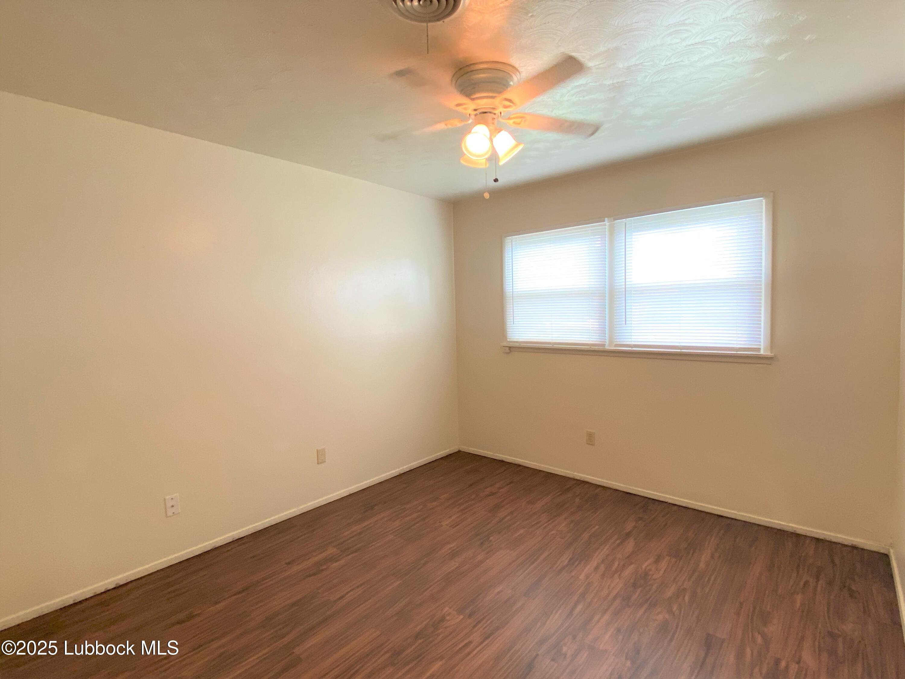 5207 39th Street Lubbock, TX 79414 - Photo 12 of 20 an empty room with a chandelier fan and wooden floor