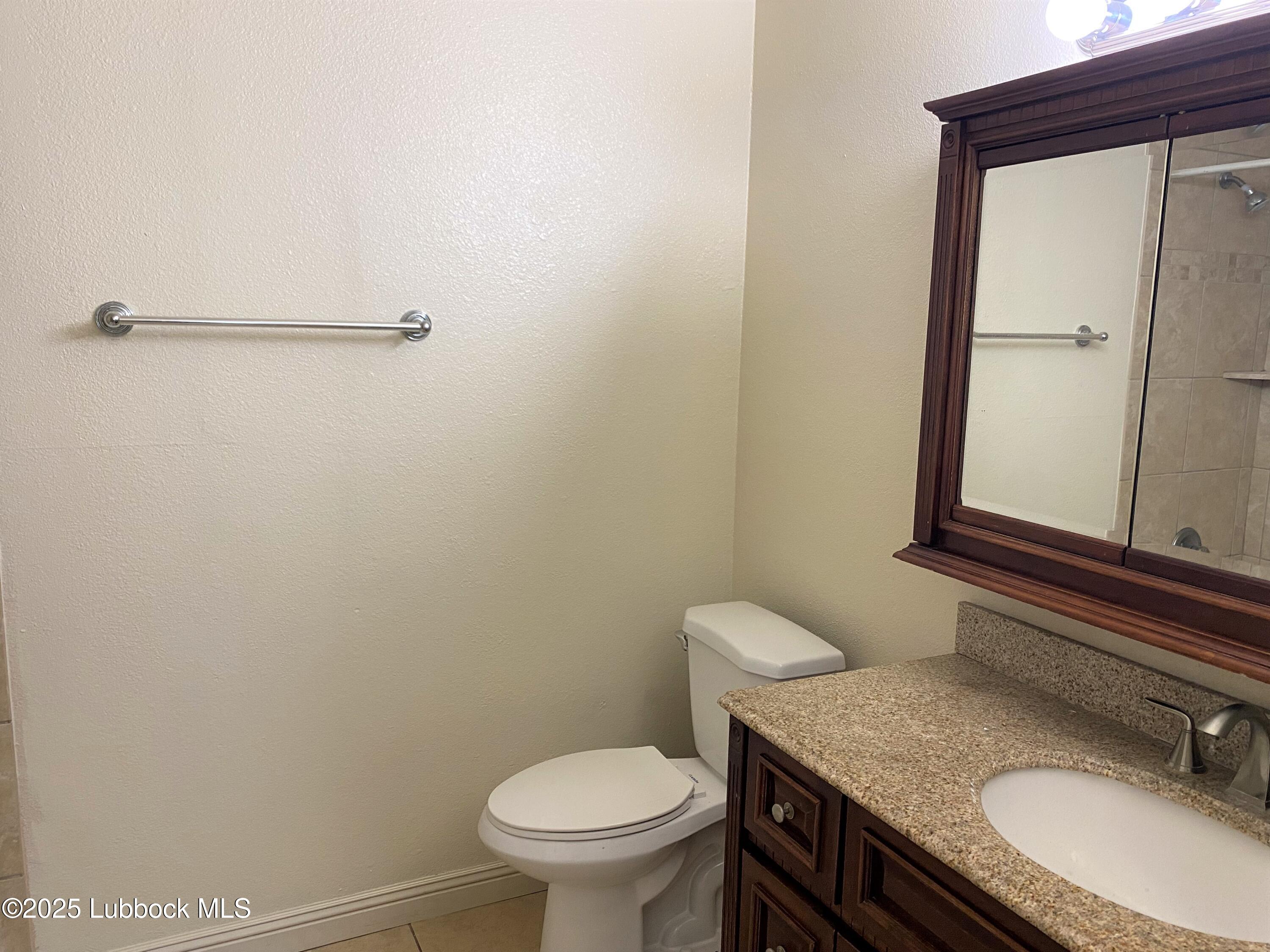 5207 39th Street Lubbock, TX 79414 - Photo 14 of 20 a bathroom with a granite countertop toilet and a sink