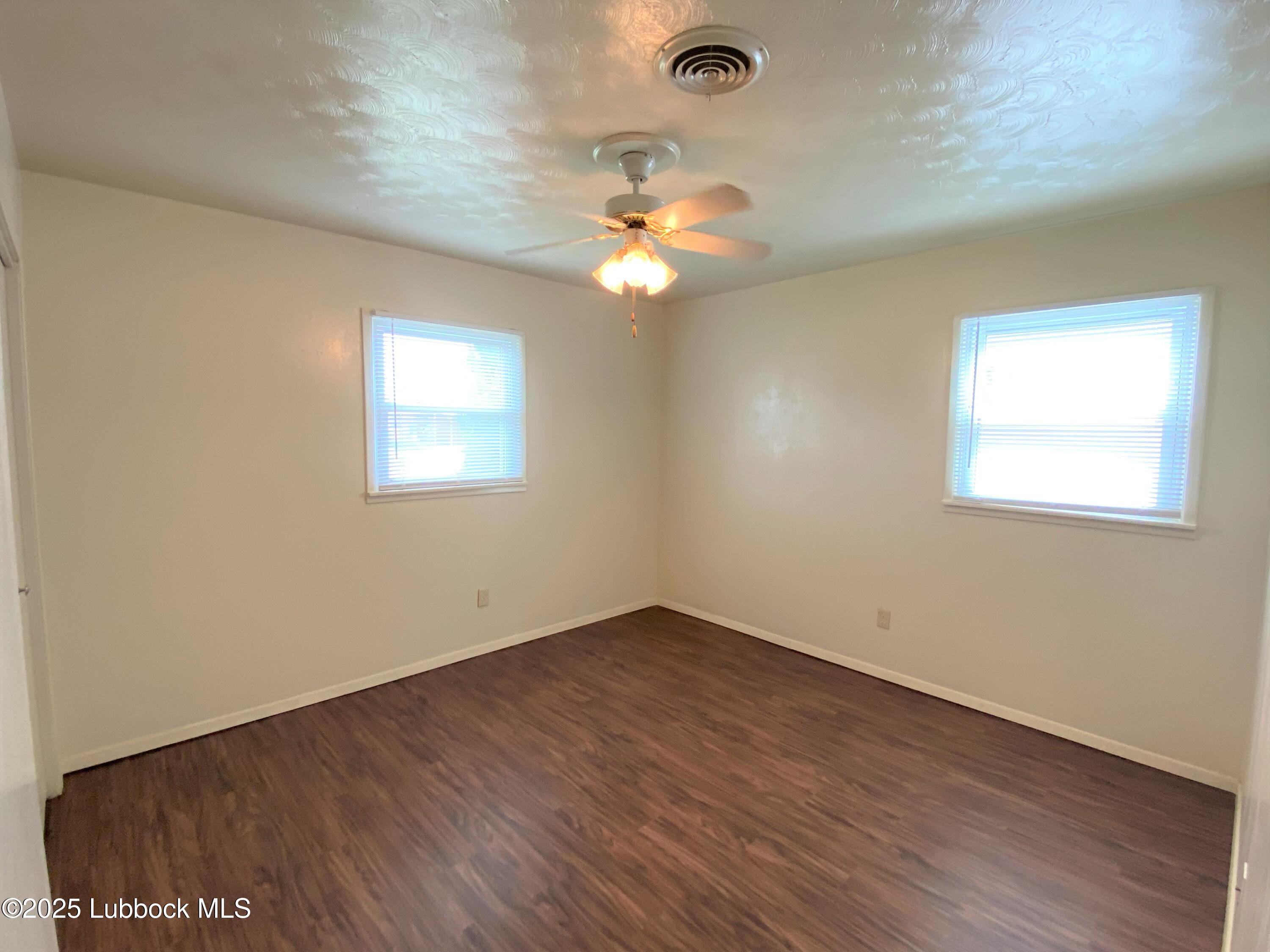 5207 39th Street Lubbock, TX 79414 - Photo 16 of 20 an empty room with wooden floor chandelier fan and windows