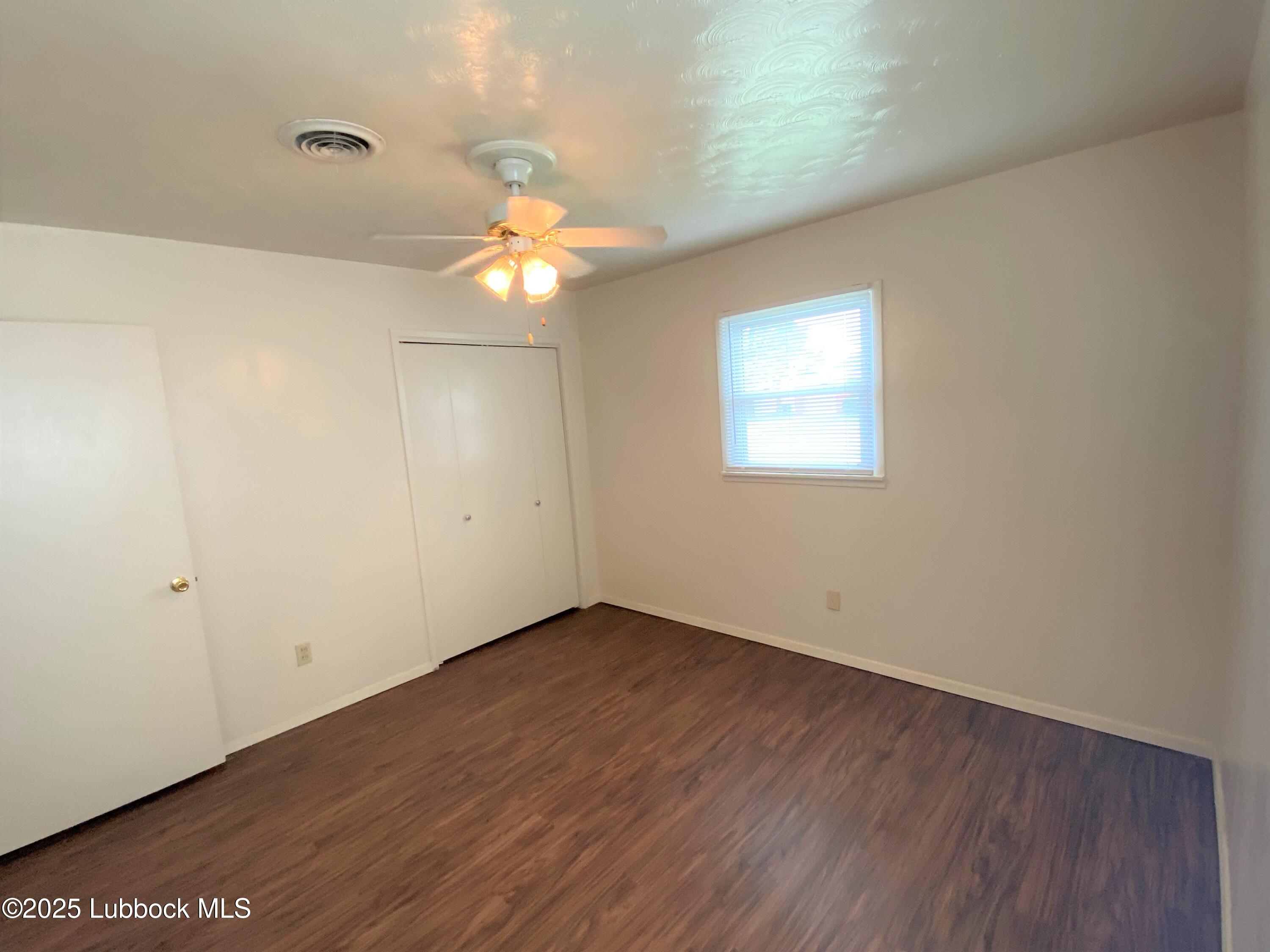 5207 39th Street Lubbock, TX 79414 - Photo 17 of 20 an empty room with wooden floor chandelier fan and windows