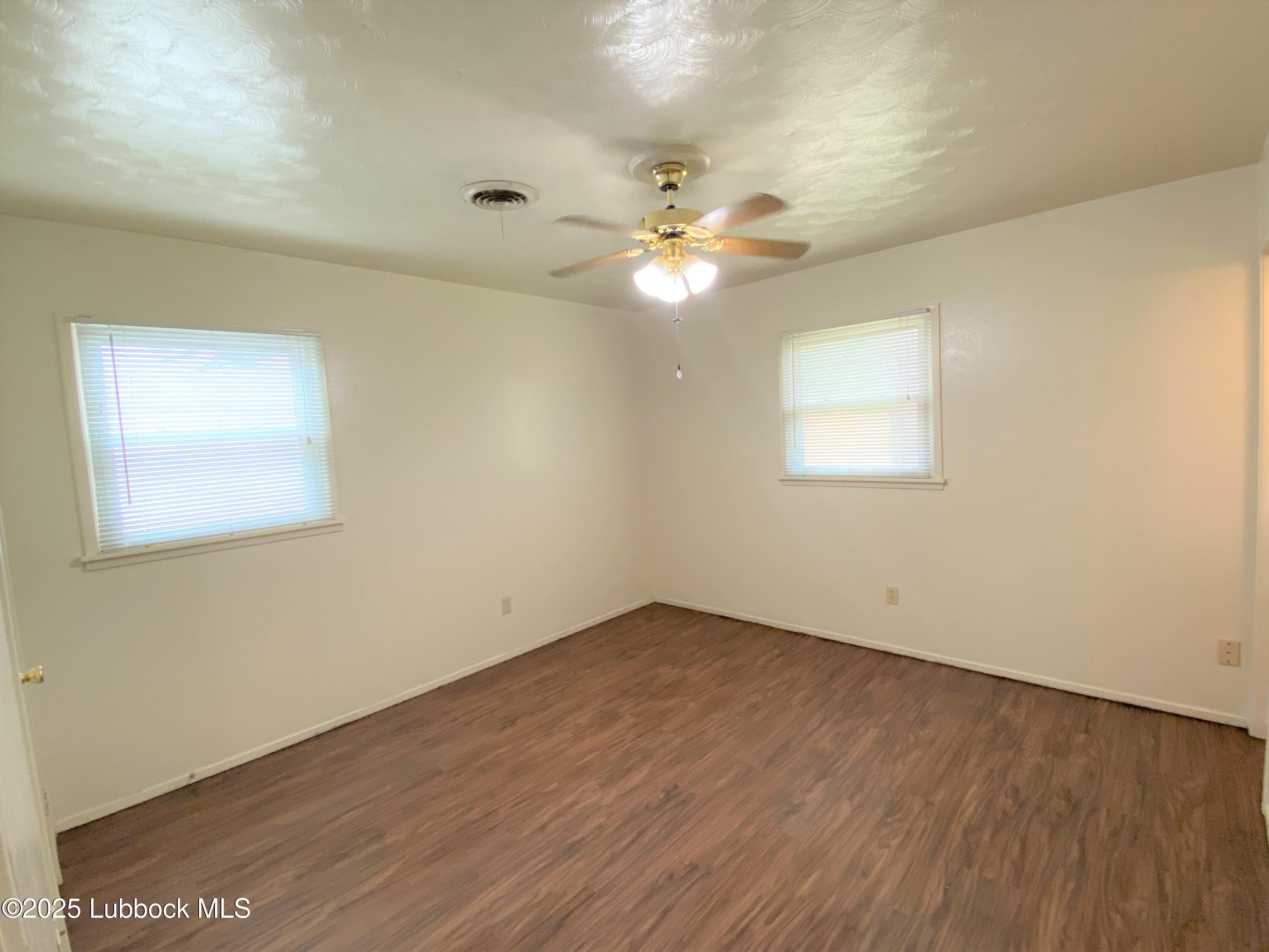 5207 39th Street Lubbock, TX 79414 - Photo 18 of 20 an empty room with wooden floor chandelier fan and windows