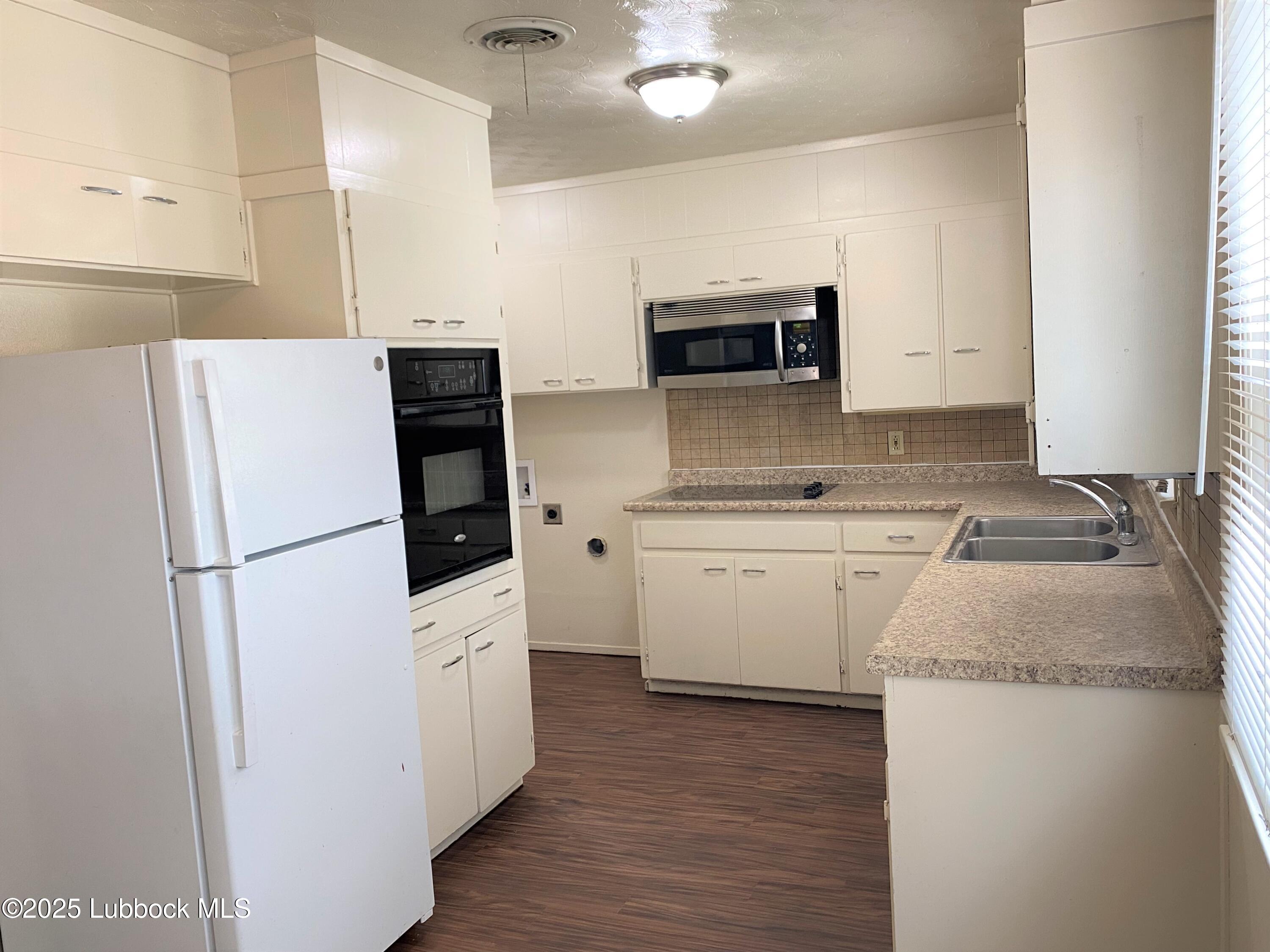 5207 39th Street Lubbock, TX 79414 - Photo 4 of 20 a kitchen with white cabinets and white appliances