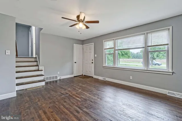 an empty room with wooden floor fan and windows