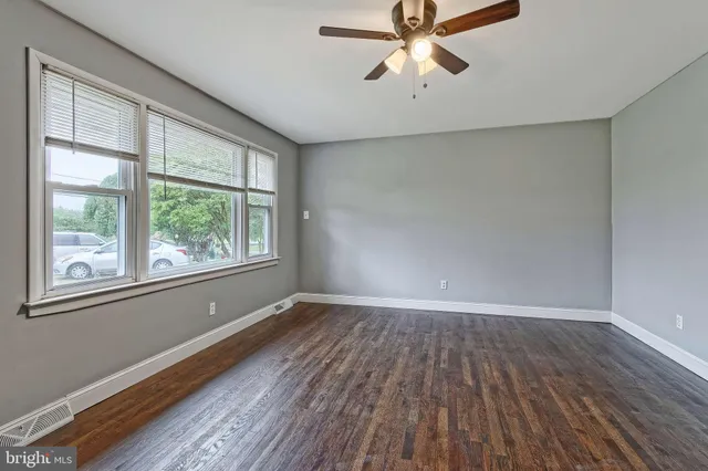 an empty room with wooden floor fan and windows